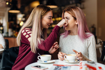 Two girls meat at coffee place and talk to each other, make conversation