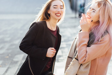 Two girls talking to each other and laughing, autumn clothing