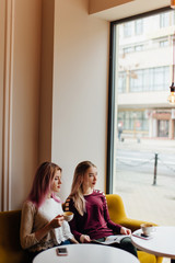 Two girls meat at coffee place and talk to each other, make conversation