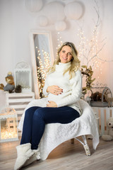 Beautiful pregnant young woman on a Christmas, having a rest on Christmas holidays before the new year. Big pregnant belly