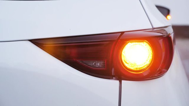 Headlight of modern car flashes. White car headlight close-up, yellow light flashing
