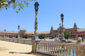 Fototapeta na wymiar Plaza de Espana in Seville Scenic View of Brightly Colored Ceramics Showcased Lanterns and Beautiful Balustrade Ornamental Parapet in Front and Main Building Architectural Complex on Background.