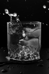 Splash in the glass of fresh water with ice on black background