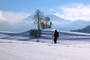 Woman is snowshoe hiking in alpine winter mountains. Bavaria, Germany.