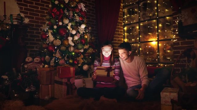 A Christmas gift. Married couple open a box with a gift. Bright light from the box. Christmas, New Year.