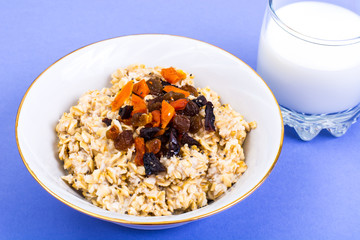 Healthy and diet food. Oatmeal with raisins, dried apricots, prunes and chia seeds on bright background