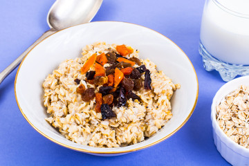 Healthy and diet food. Oatmeal with raisins, dried apricots, prunes and chia seeds on bright background