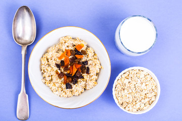 Healthy and diet food. Oatmeal with raisins, dried apricots, prunes and chia seeds on bright background