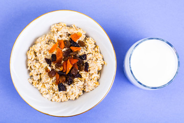 Healthy and diet food. Oatmeal with raisins, dried apricots, prunes and chia seeds on bright background