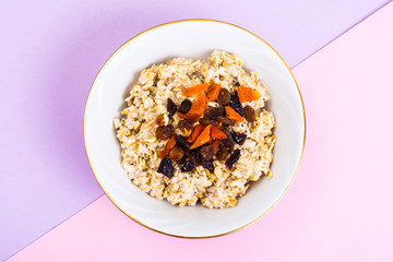 Healthy and diet food. Oatmeal with raisins, dried apricots, prunes and chia seeds on bright background