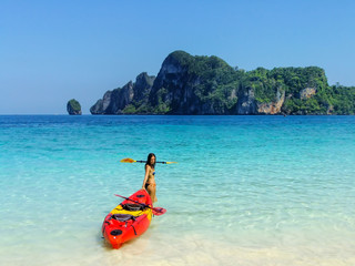 Young woman standing with kayak at Ao Yongkasem beach on Phi Phi Don Island, Krabi Province, Thailand