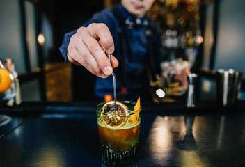 Bartender is making cocktail at bar.