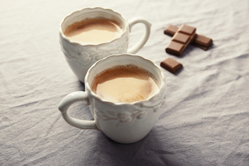 Ceramic cups with delicious coffee on fabric