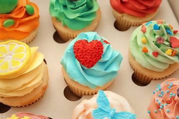 Obraz na płótnie Canvas Tasty colorful cupcakes in open paper box