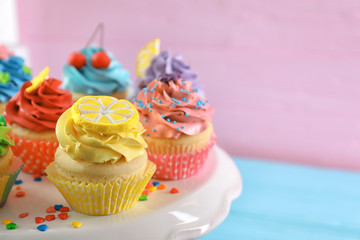 Stand with tasty bright cupcakes on color background, closeup