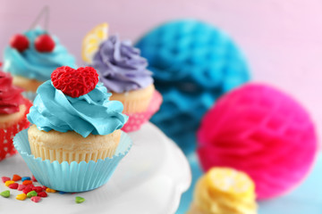 Stand with tasty bright cupcakes on blurred background, closeup