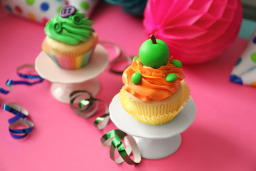 Tasty bright cupcakes on color background