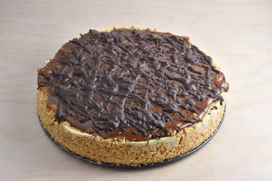 Beautiful Turtle, Chocolate And Caramel Covered, Cheesecake With Graham Cracker And Pecan Nut Crust On A Wooden Table.