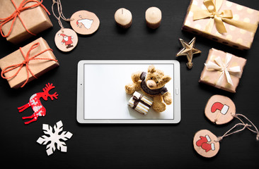 New year's background on a black desk decorated with toys, presents, Christmas tree. Bright colored background symbolizes the new year celebration. Great useful template with a tablet.