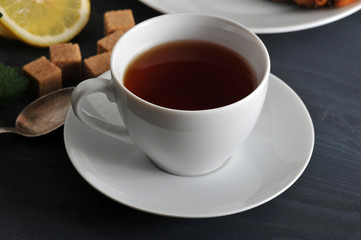 black tea in a mug on a saucer, lemon and mint