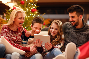 Obraz na płótnie Canvas Christmas entertainment at home family watching video on digital tablet.