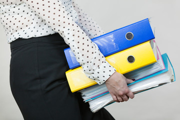 Woman holding heavy colorful binders with documents