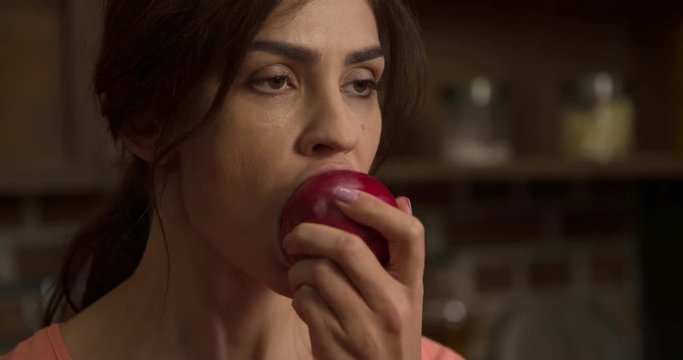 Woman eating red apple 4k slow-motion video. Female on modern home kitchen biting fruit. Healthy food breakfast lunch