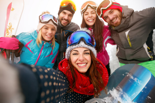 happy friends having fun on snow. Snowbarders and skiers group team making selfie