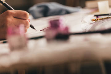 Beautiful blonde woman artist drawing with a brush and pain in her art studio