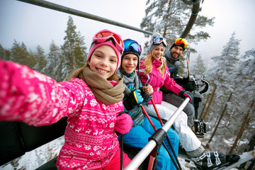 Skiing, ski lift, ski resort - happy family skiers on ski lift making selfie