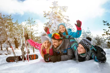 Afwasbaar Fotobehang Wintersport smiling family enjoying winter vacations in mountains on snow