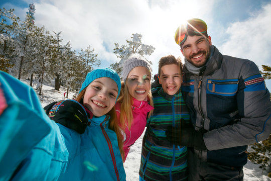 family laughing and making selfie on winter ski vacation
