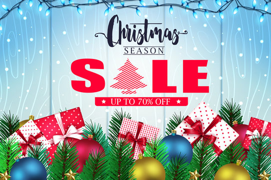 Christmas Season Sale Banner in Blue Wooden Background with Falling Snow, Christmas Lights, Gifts, Balls, Stars and Pine Leaves Promotional Design for Holiday. Vector Illustration
