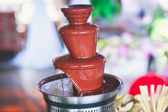 Vibrant Picture of Chocolate Fountain Fontain on a children kids birthday party with a kids playing around and dipping marshmallows and fruits into the fountain
