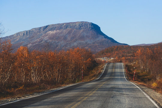 Beautiful vibrant fall autumn landscape of national park near border of Finland, Sweden and Norway, with mountains, camping place, road and forest