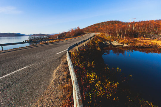 Beautiful vibrant fall autumn landscape of national park near border of Finland, Sweden and Norway, with mountains, camping place, road and forest