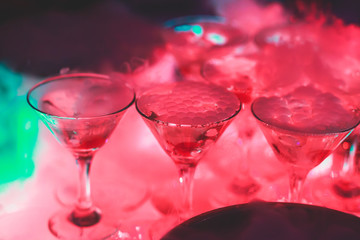 Beautiful pyramid line of different coloured alcohol cocktails with mint on christmas party, tequila, martini, vodka, and others on decorated catering bouquet table on