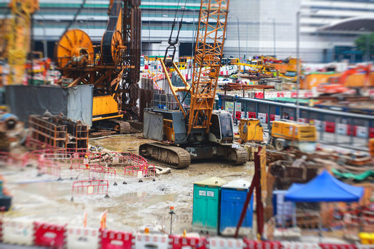 A large construction site in the city, the process of massive buliding construction with heavy vehicle at work, excavator, elevating crane and bulldozer