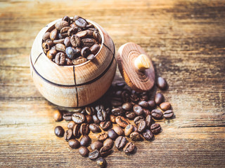 Coffee beans in a decorative barrel on a wooden table