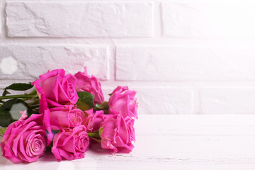 Bunch of pink  roses  flowers on white wooden background against white wall.