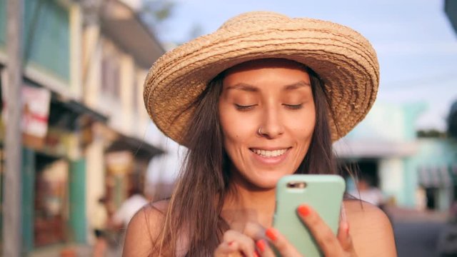 Young Carefree Happy Hipster Woman in Straw Hat Mixed Race Tourist Girl Using Mobile Phone at Vintage Buildings at Old Town Street. Thailand. 4K, Slowmotion.