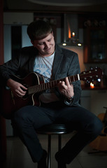 Obraz premium The Guitarist Guy plays the guitar in a bar in a beautiful setting on a high bar stool