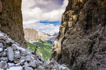 hiking trail and trail marker in the Italian Dolomites through a steep and narrow gorge after a fresh snow fall in autumn