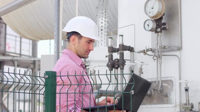 Engineer with laptop check parameters on instrumentation at chemical plant