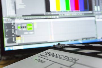 Movie clapper and editing room in background