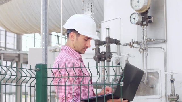 Operator with laptop check parameters on instrumentation at chemical plant