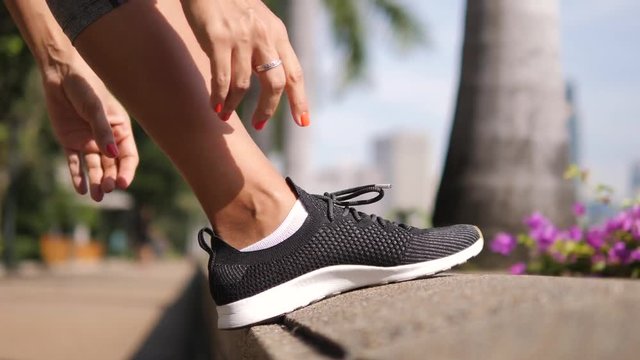 Young Fitness Woman Tying Sneakers Running Shoe Laces in Park. 4K, Close Up. Bangkok, Thailand.