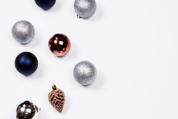 Christmas holiday background. Blue and silver glitter ball and gold pine cone christmas ornaments on a white background with copy-space. Top view.