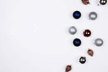Christmas holiday background. Blue and silver glitter ball and gold pine cone christmas ornaments on a white background with copy-space. Top view.