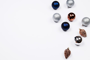 Christmas holiday background. Blue and silver glitter ball and gold pine cone christmas ornaments on a white background with copy-space. Top view.